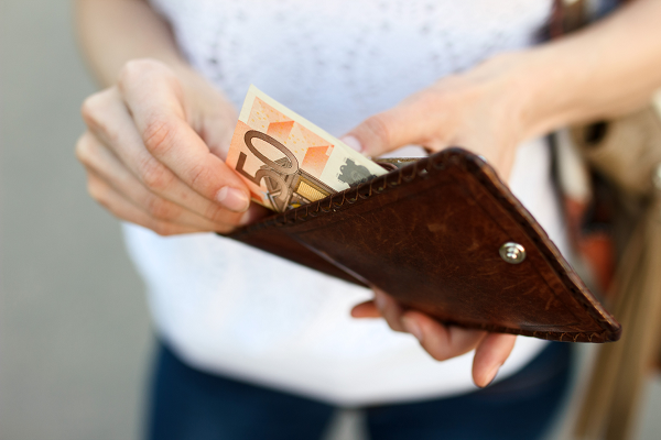 Geldbeutel Eine unscharfe Frau im Hintergund hält einen Geldbeutel, aus dem sie einen 50 Euro-Schein heraus holt