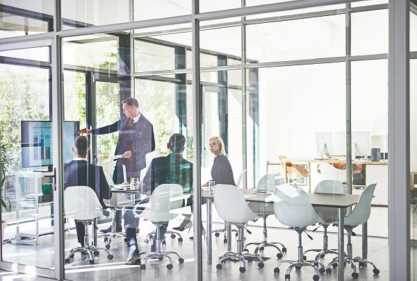 Meeting von 4 Kollegen in einem verglasten Büro mit weißen Stühlen