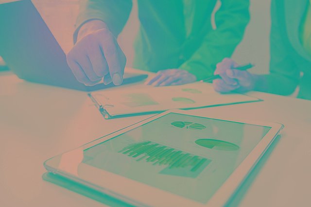 2 Menschen betrachten Grafiken auf Laptop und Tablet