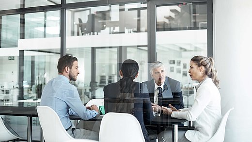 4 Kollegen sitzen um einen Tisch und diskutieren