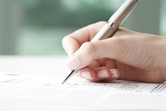 Weibliche Hand die auf ein Blatt Papier schreibt
