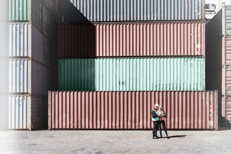 Container Mehrere bunte Frachtcontainer übereinander mit 2 Menschen davor