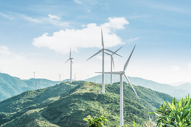 Windräderpark Viele grüne Hügel mit mehreren Windrädern.